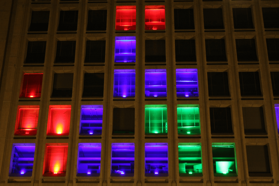 Closeup photo of 5 floors of the Green Building with varying colors in each window representing tetris shapes
